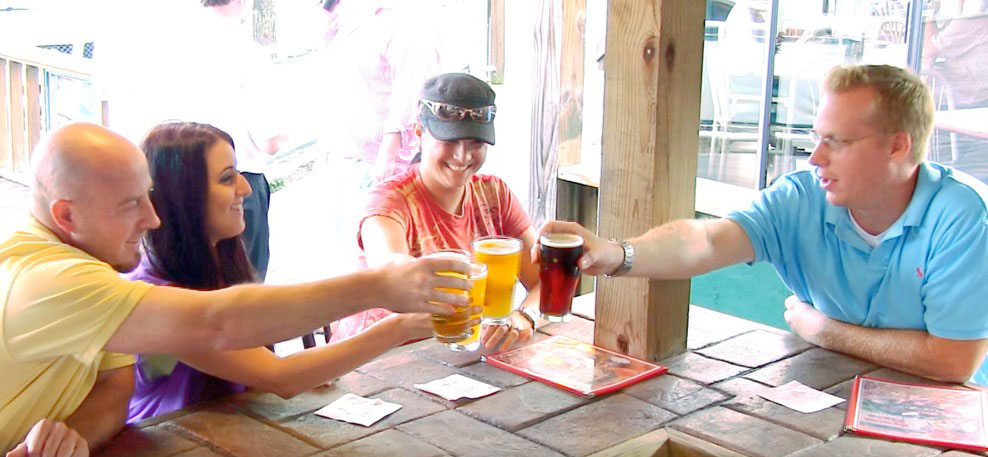 Photo of friends toasting at the outdoor bar at Grotto Pizza in Harveys Lake